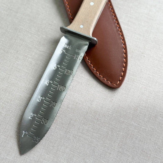 Knife with leather sheath on a light gray background