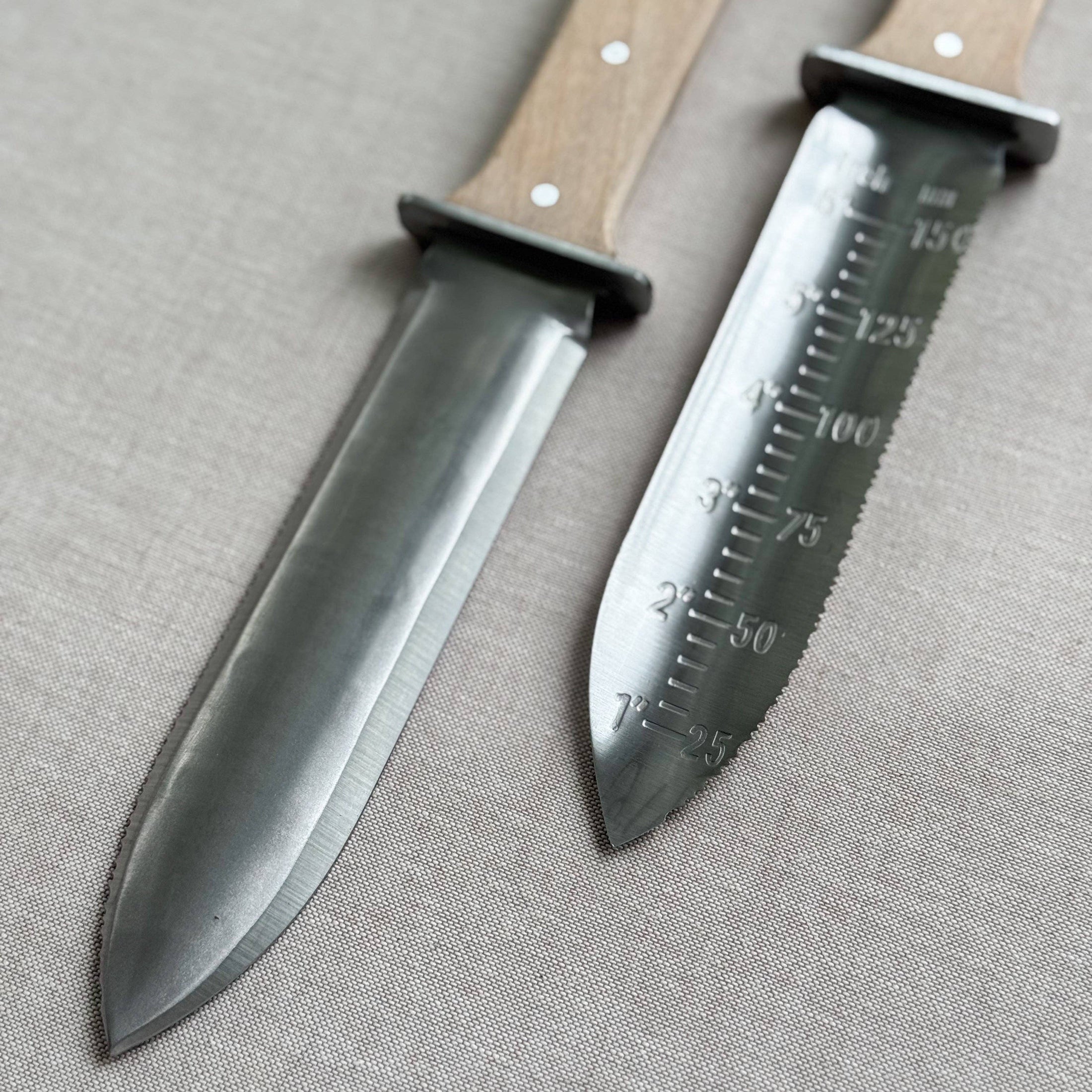 Two knives with wooden handles on a gray fabric background